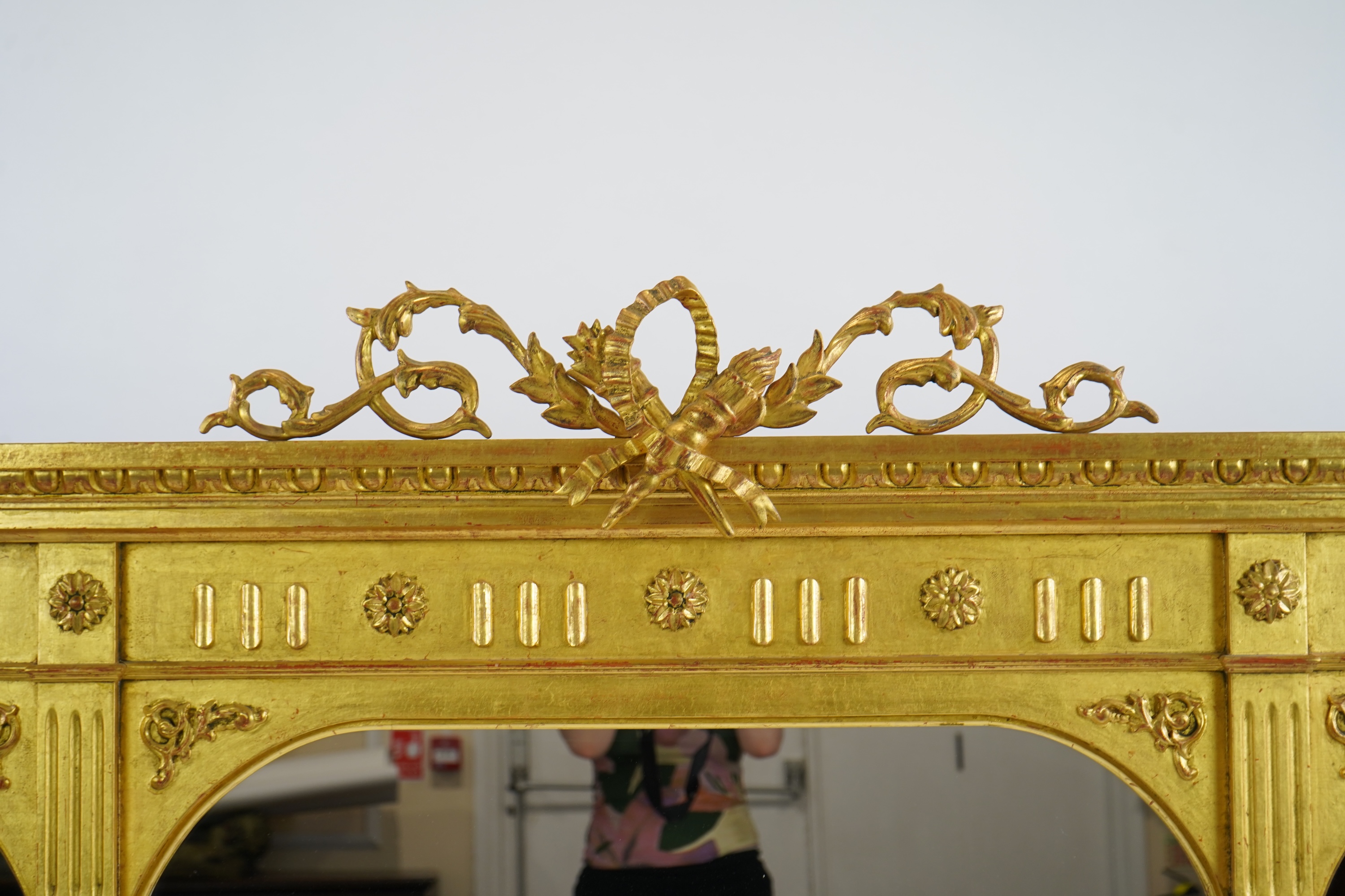 A Victorian style giltwood and composition triple plate overmantel mirror, with foliage scroll torch pediment over a flower head frieze and fluted pillars, 222cm wide,152cm high